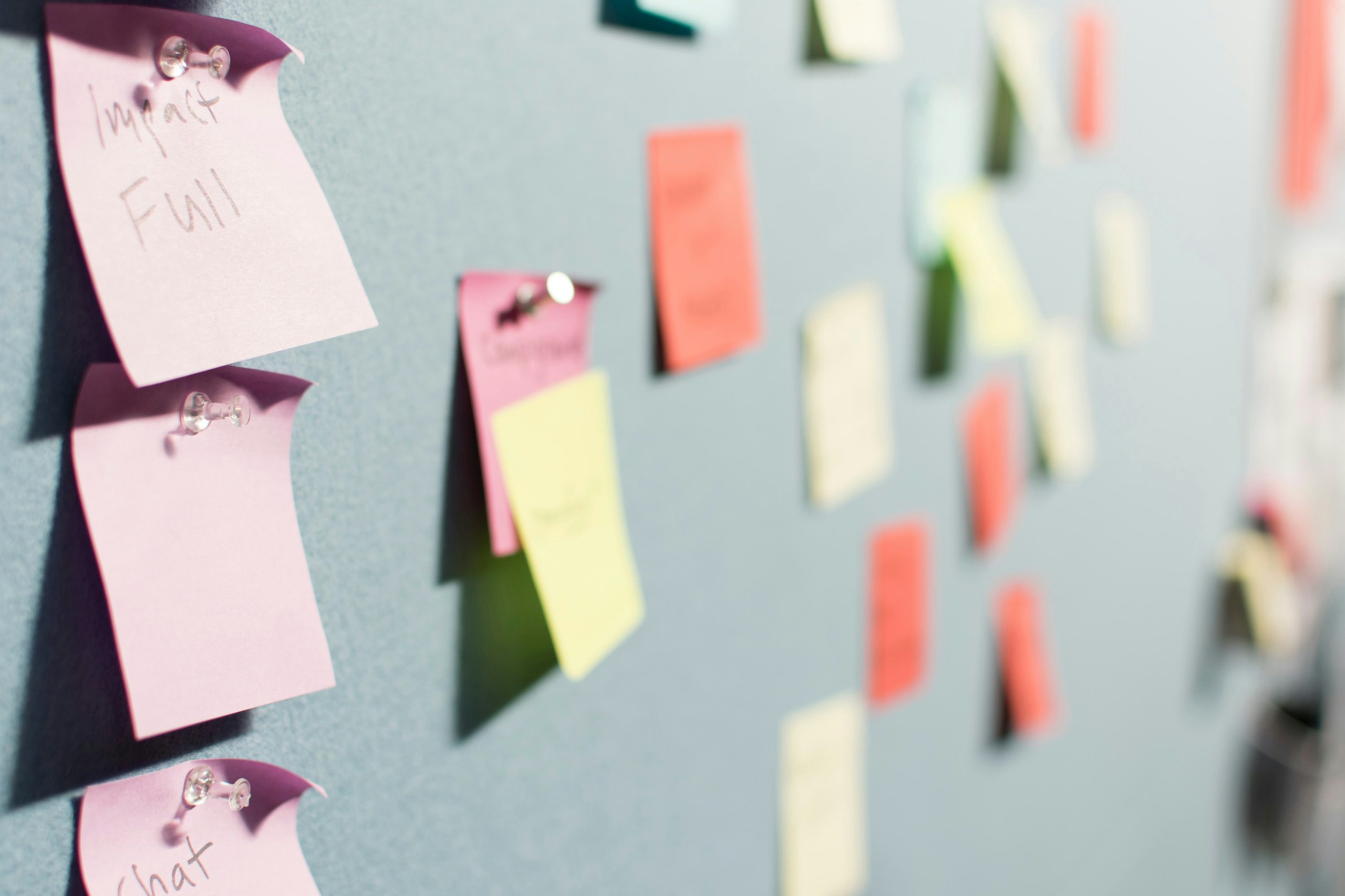 colorful sticky notes pinned to a corkboard from a brainstorm session, showing task planning