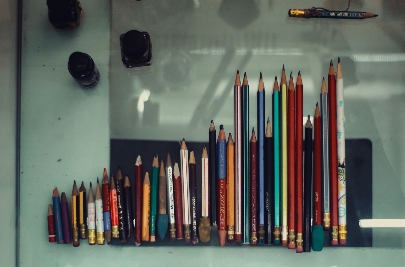 a collection of colored pencils arranged on a flat surface in a rainbow of color